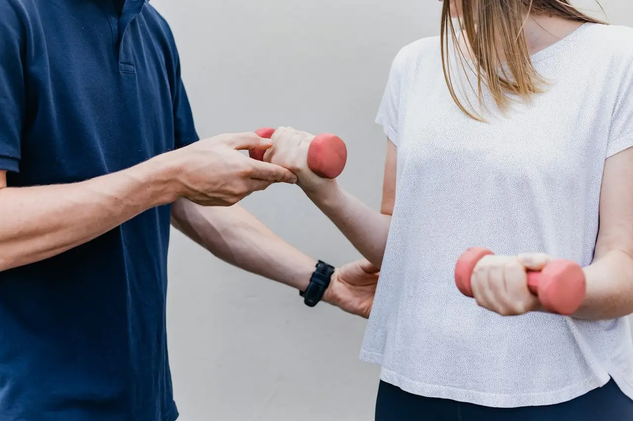 A therapist guiding a patient through a dumbbell exercise