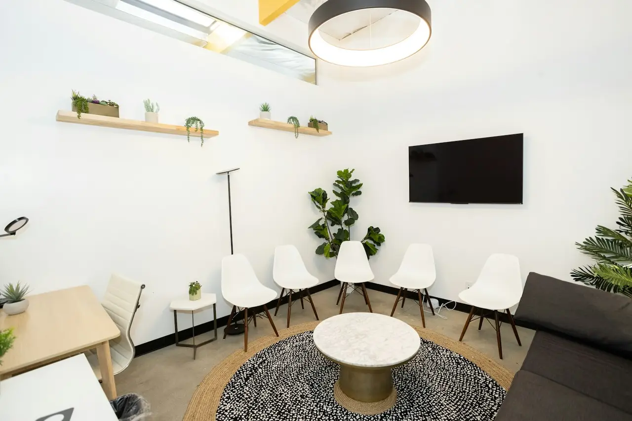 A bright, modern waiting room with white chairs and plants