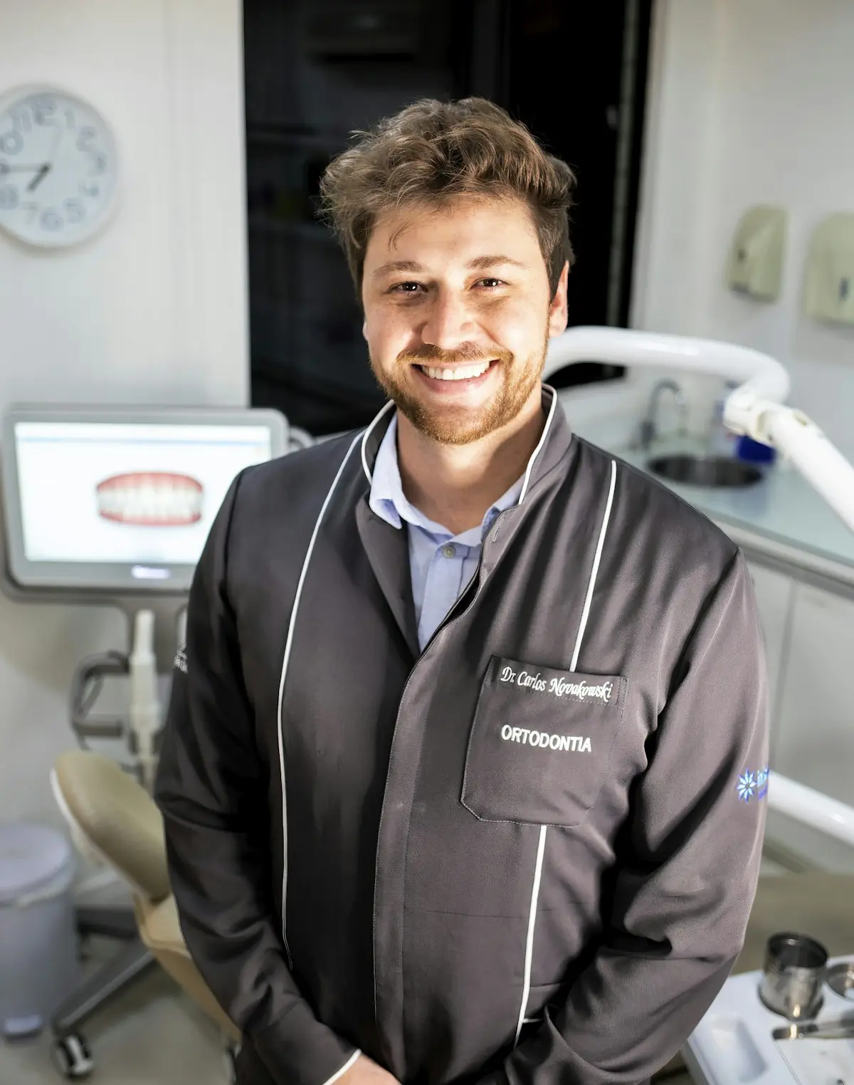 A dentist standing in a treatment room, smiling