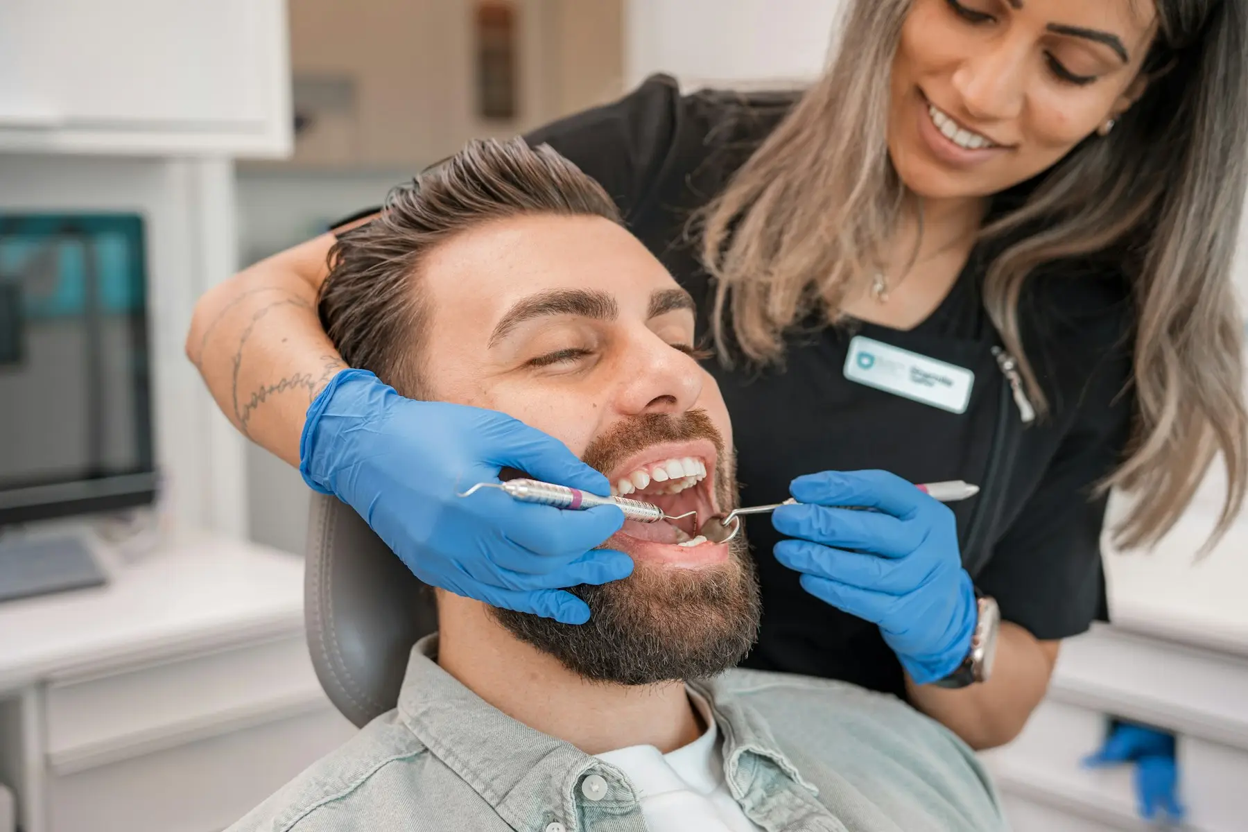A dentist in blue gloves examining a smiling patient