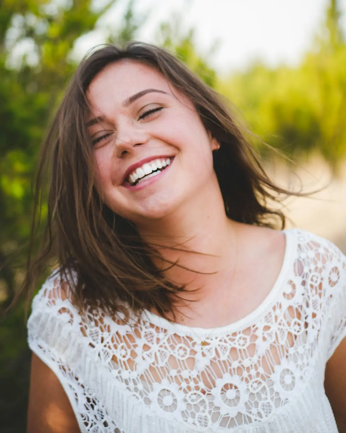 A woman in a white top smiling outdoors