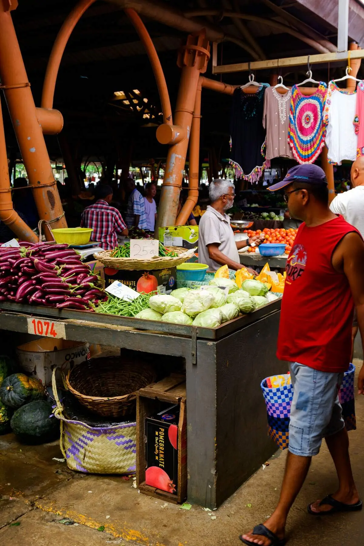 People shopping at a produce stand under a canopy