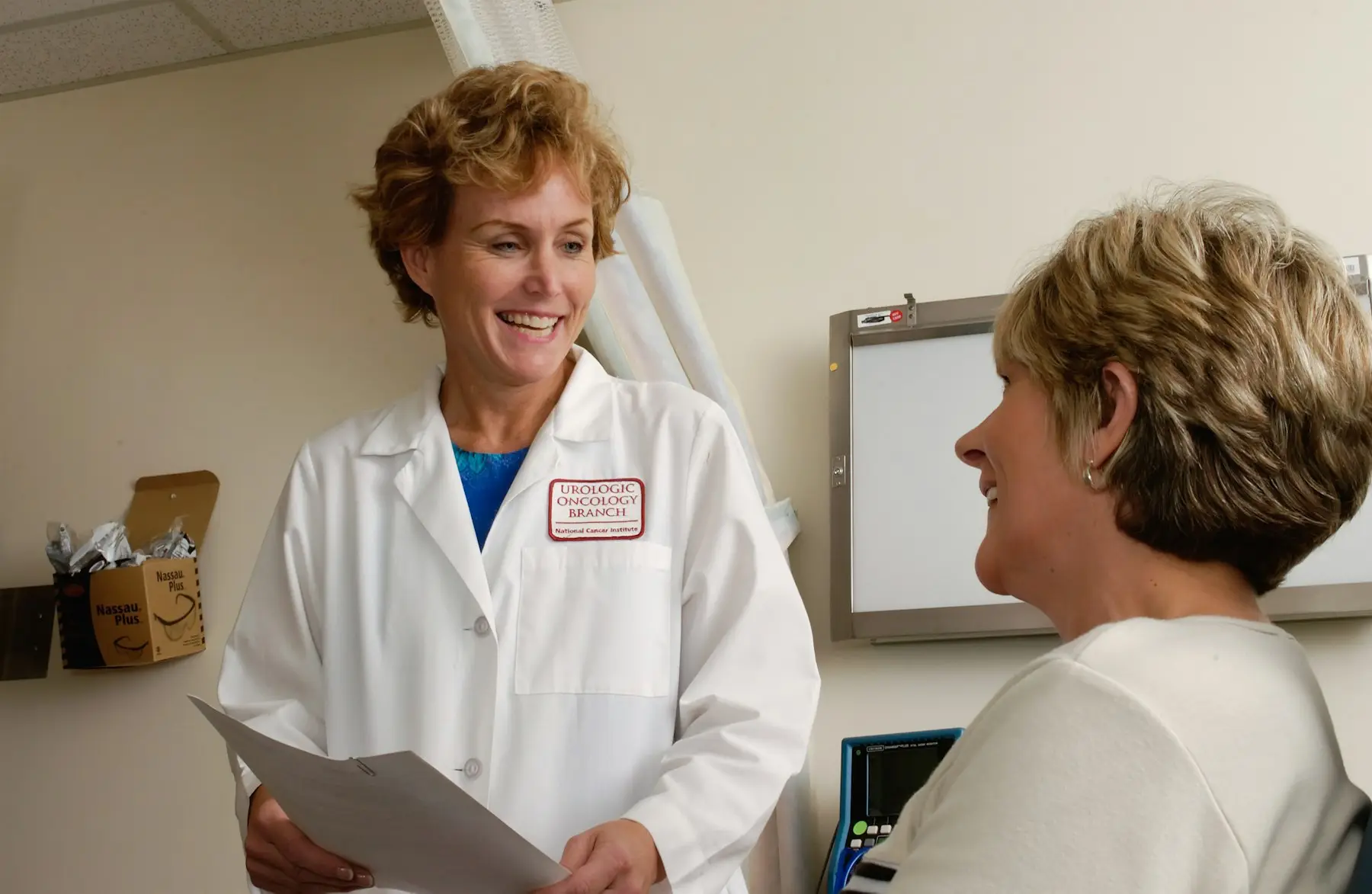 A smiling doctor in a white coat talking with a patient