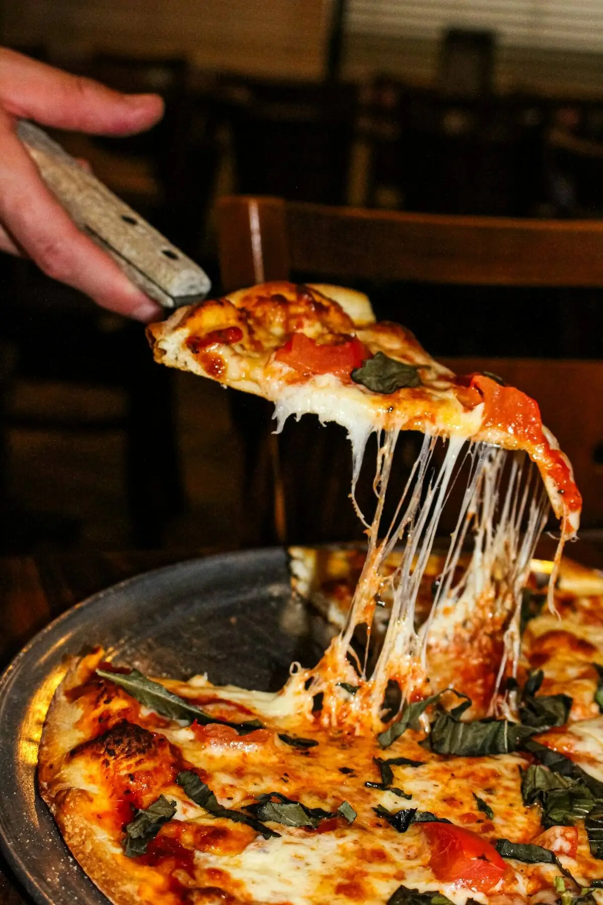 A slice of pizza lifted with the cheese stretching