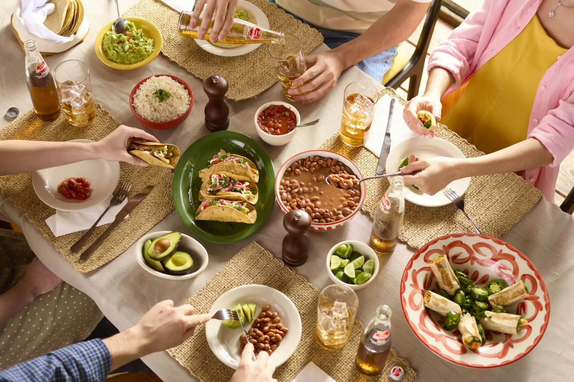 Friends reaching across a table full of shared plates