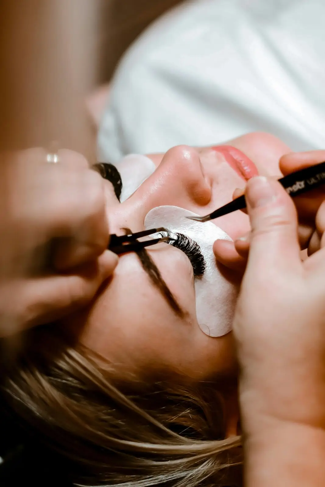 A lash artist applying extensions to a client